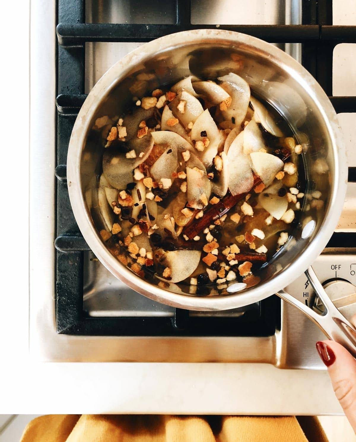 A grey metal pot on a stove has food cooking in it.